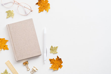 Autumn feminine desk table with paper notebook, glasses, maple leaves on white background. Blogger...