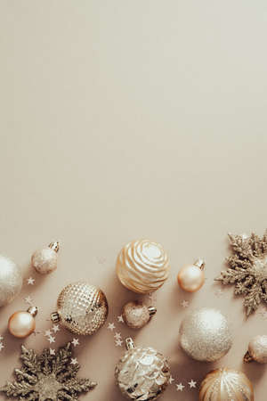 Elegant Christmas poster mockup with golden balls decorations and snowflakes on pastel beige background. Flat lay, top view.の写真素材