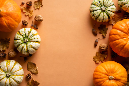 Autumn frame made of pumpkins, dry oak leaves, nuts, acorns on vintage orange background. Thanksgiving day greeting card design.の写真素材
