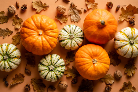 Autumn composition. Flat lay pumpkins, fallen oak leaves, nuts on vintage orange background....