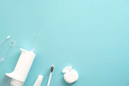 Oral water irrigator, toothbrush, dental floss on blue background. Flat lay, top view, copy space. Dental clinic banner design.の写真素材