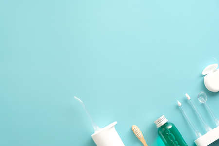 Dental care products on blue background. Flat lay composition with water flosser irrigator, mouthwash, dental floss, toothbrush.の写真素材