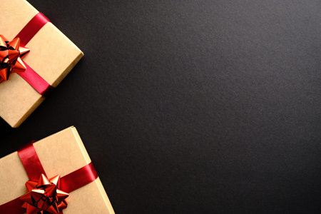 Christmas gift boxes decorated red ribbon bow on black background. Flat lay, top view, copy space.