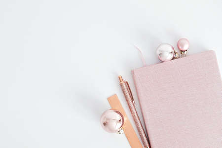 Christmas holiday festive workspace top view. Glamor pink notebook, balls and office accessories on white background. Top view with copy space. Minimal style.の写真素材