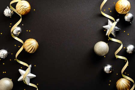 Merry Christmas and Happy New Year greeting card design. Christmas golden and silver ornaments on black background. Top view. Festive Christmas frame, banner mockup.の写真素材