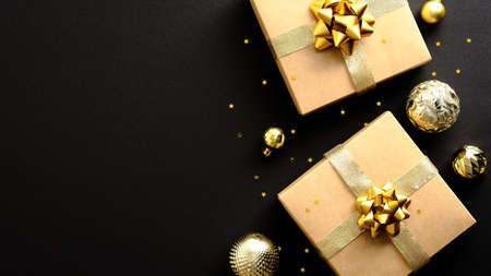 Luxury Golden Christmas gifts and balls on dark black background. Christmas banner mockup. Top view with copy space.の写真素材