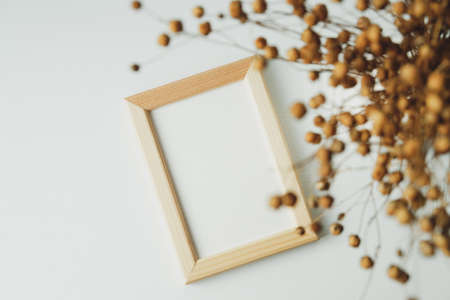 Picture frame mockup and dried flowers on white background. Flat lay, top view, copy space.の写真素材