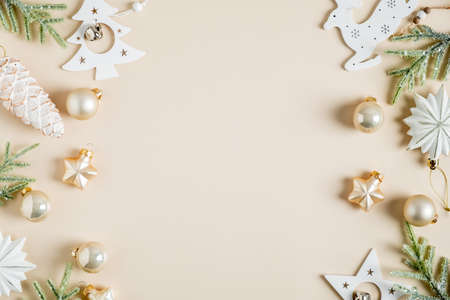 Christmas frame. Elegant Christmas card with fir branches, boho style white stars, baubles, pine cone decoration on beige background. Flat lay, top view, copy spaceの写真素材