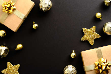 Christmas composition. Flat lay gifts, golden balls star decoration on dark black background. Merry Christmas and Happy New Year greeting card design.の写真素材