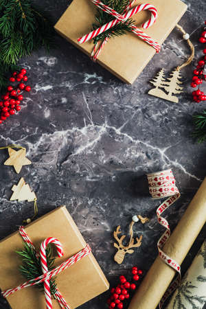 Vintage Christmas vertical background with Christmas gifts decorated striped ribbon, fir branch, candy cane and wooden decoration on stone table. Flat lay, top view, copy space.の写真素材