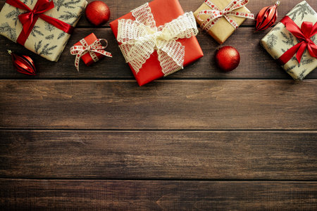 Christmas background. Festive Christmas gift boxes and red baubles on wooden table. Christmas frame...
