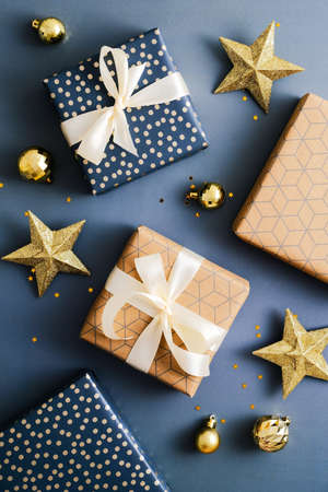 Christmas composition. Elegant gift boxes with golden stars and baubles on dark blue background. Luxury Christmas card.の写真素材