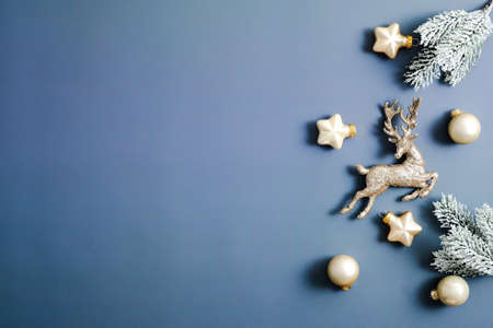 Blue Christmas background. Frame made of gold stars, reindeer, baubles decorations, fir branches. Copy space, flat lay.の写真素材