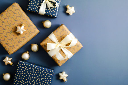 Christmas flat lay composition. Craft paper and blue gift boxes on dark blue background. Merry...