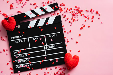 Movie clapper and Valentines Day hearts on pink background. Flat lay, top view. Love, romance concept.の写真素材