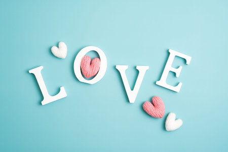 Happy Valentines Day creative layout. Love word and knitted hearts on blue background.