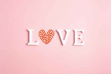 Word Love made of white letters and heart shaped confetti on pink background. Happy Valentines Day concept. Minimal style.の写真素材