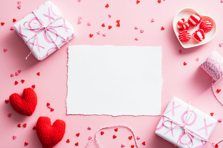 Happy Valentines Day composition. Flat lay blank paper card, gift boxes, red hearts on pastel pink...