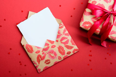 Happy Valentines day concept. Flat lay romantic letter and gift box on red background. Envelope with...