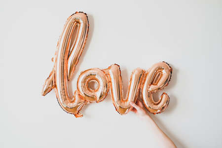 Woman's hand holding foil balloon Love. Greetings for Valentine's Day, Mother's day, Birthday.の写真素材