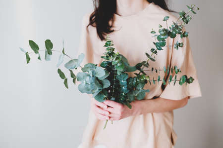 Woman holding bouquet made of eucalyptus green branches in her hands.の写真素材