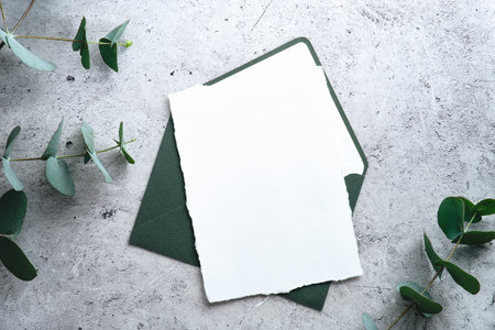 Wedding stationery set. Wedding invitation card mockuyp, envelope green, eucalyptus branches on concrete background. Flat lay, top view, copy space.の写真素材