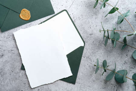 Wedding stationery set. Wedding invitation card template, green envelope, eucalyptus branches on concrete background. Flat lay, top view, copy space.の写真素材