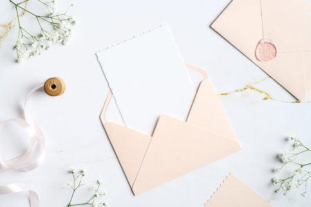 Envelope with wedding invitation card inside on marble table. Wedding stationery set. Flat lay, top...