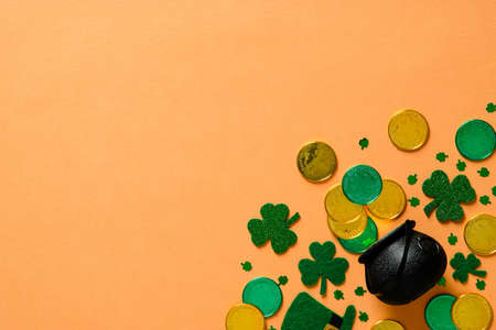 St Patricks Day banner design with pot of gold, shamrock clover leaves on orange background. Flat lay, top view, copy space.の写真素材