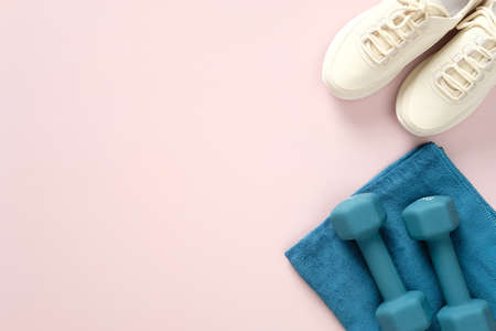 Sneakers, towel and dumbbells on pastel pink background. Fitness, workout, healthy lifestyle concept. Flat lay, top view, copy space. Sport blog banner design.の写真素材