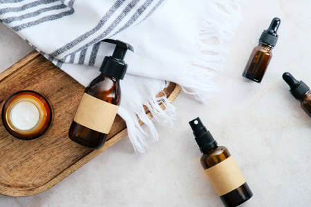 Amber glass cosmetic bottles and towel on stone table in bathroom. Natural organic beauty products set. skincare concept.の写真素材