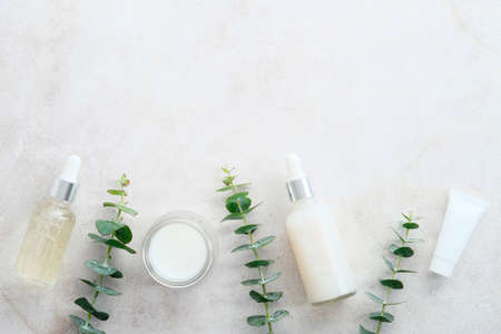 Transparent cosmetic bottles, tube, jar of cream with eucalyptus leaves on stone table. Natural, organic, herbal beauty products packaging design.の写真素材