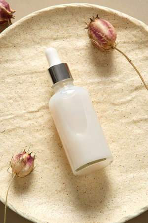 Dropper bottle with serum lotion or essential oil with dried flowers on stone plate top view. skincare concept.の写真素材