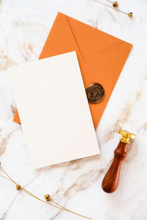 Wedding invitation card, brown envelope, wax seal stamp on marble desk table with dry flowers. Flat lay, top view, copy space.の写真素材
