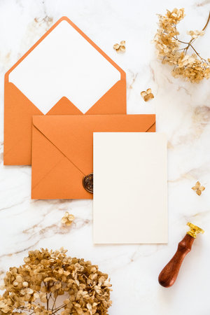 Wedding invitation card, brown envelopes, dry flowers on marble table. Flat lay, top view, copy...