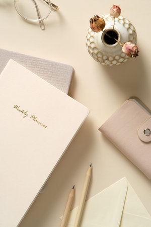 Flat lay stylish feminine home office workspace. Top view paper notebook, envelope, pencils,...