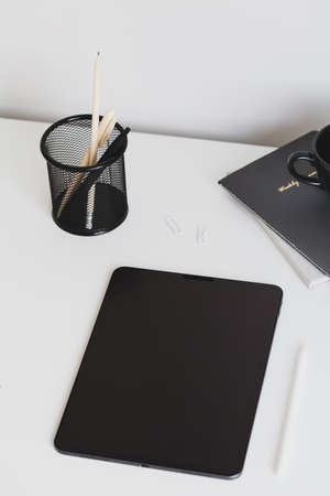 Digital tablet on office desk table with stationery top view. Modern, minimal style workspace.の写真素材