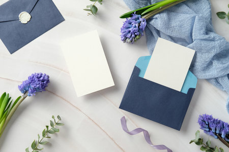 Set of elegant wedding invitation card, navy blue envelopes, purple hyacinth flowers on a desk marble with a light blue fabric. Flat lay, top view, copy spaceの写真素材