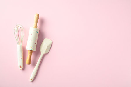 Baking utensils on a pink background, including a whisk, rolling pin, and spatula. Culinary conceptの写真素材