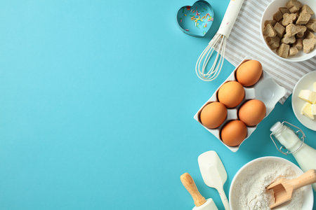 Baking ingredients and tools on a blue background, including eggs, flour, butter, milk, a rolling pin, and cookie cutters. Perfect for illustrating baking recipes, food blogs, or culinary artの写真素材