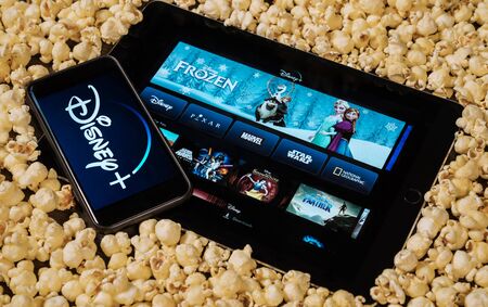 Grand Prairie, TX/USA - AUG 2019: Disney plus on smartphone and iPad/tablet surrounded by popcorn. Disney+ is a new streaming subscription service.のeditorial素材