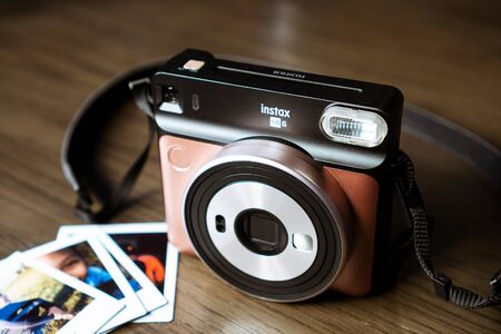 Grand Prairie, TX/USA Dec 2019: Instax Square camera with polaroid prints on wooden table. Instax cameras are a Fujifilm productのeditorial素材