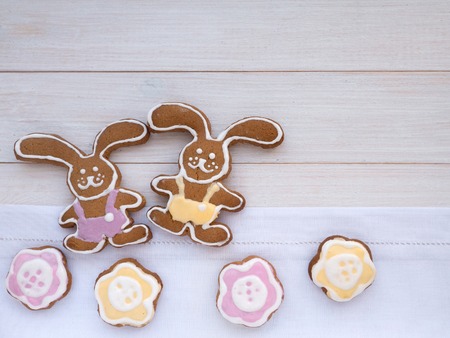 Two Easter Bunny and flower shaped cookies on the white wooden backgroundの写真素材