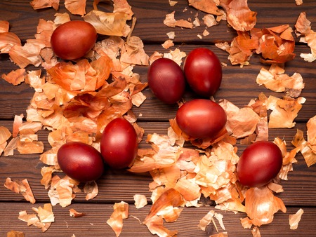 Russian traditional red painted Easter eggs and onion peel on the textured wooden backgroundの写真素材