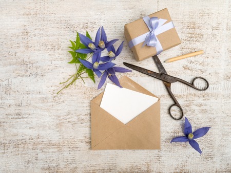 Gift box, blue flowers and envelope with greeting card on the wooden painted boardの写真素材