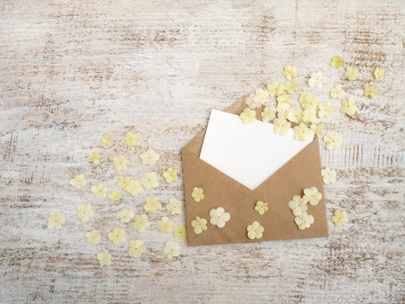 Craft paper envelope with blank card and white viburnum flowers 
on the rustic white painted...