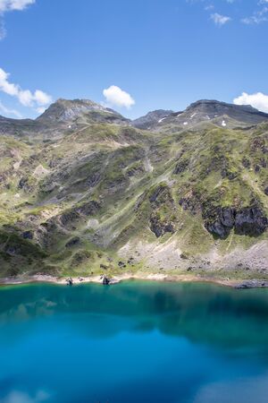 Mountain landscape near the Saliencia glacial lakes. Calabazosa lake in the Somiedo national park, Spain, Asturias. Turquoise crystal clear water. White snow spots.の写真素材