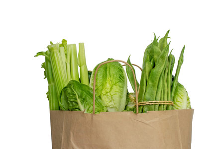 Green vegetables in the brown shopping kraft paper bag isolated on white