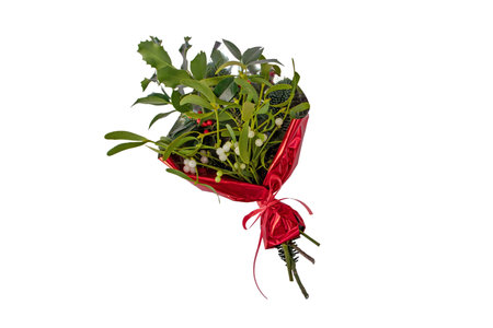Bouquet of Christmas holly, mistletoe and fir tree in red wrapping isolated on whiteの写真素材