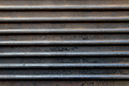 Dark horizontal ribbed rusted grunge background. Old cast iron pan grill surface